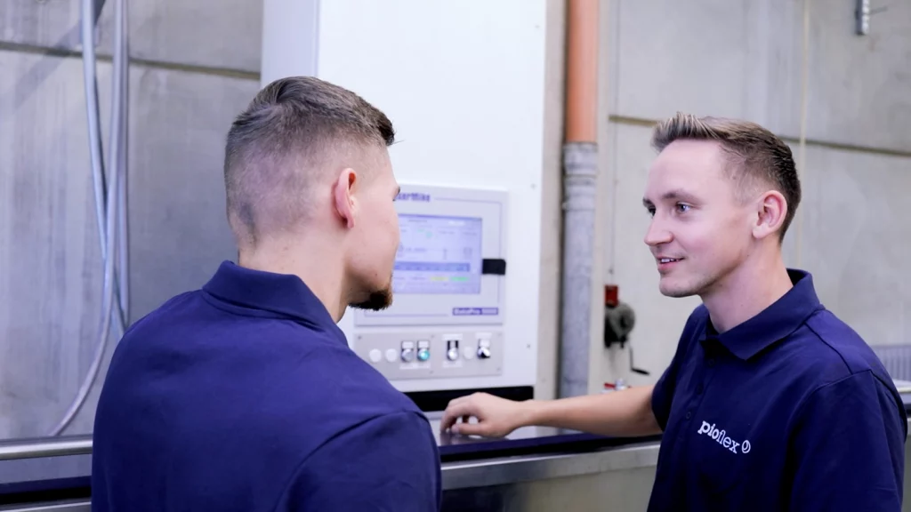 2 Personen unterhalten sich vor einer Produktionsmaschine