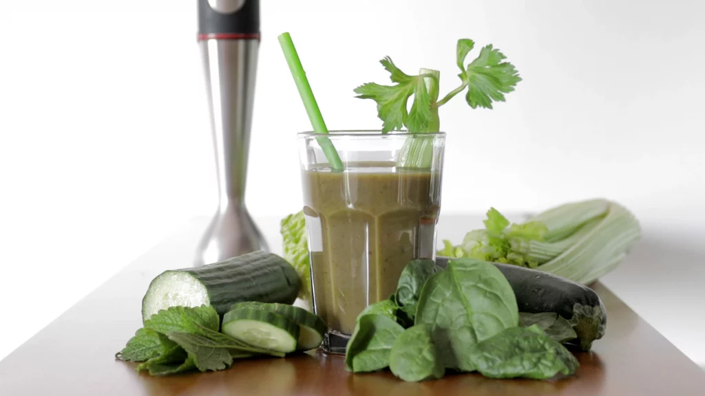 Ein grüner Smoothie mit seinen Zutaten dekoriert